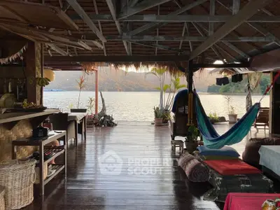 Stunning open-air living space with lake view, featuring hammock and rustic decor.