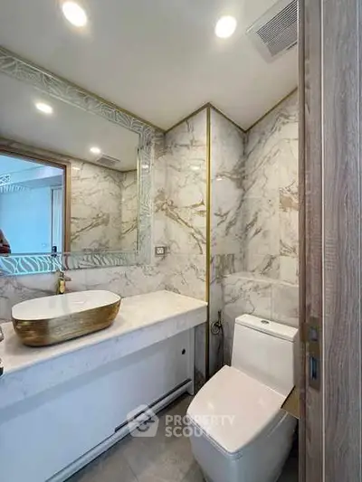 Luxurious marble bathroom with elegant vessel sink and modern fixtures.