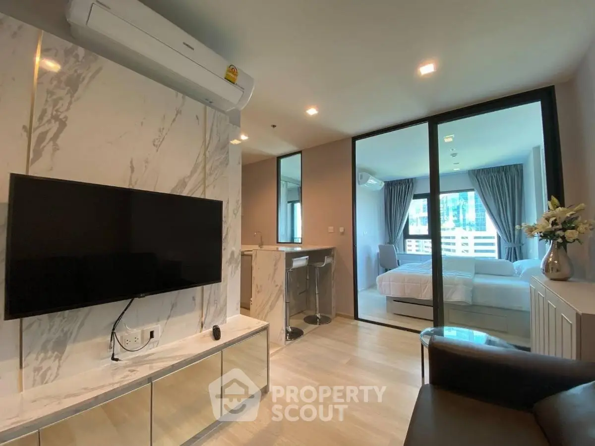 Modern living room with TV and view into stylish bedroom