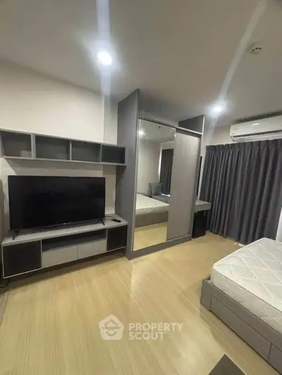 Modern bedroom with mirrored wardrobe and sleek TV unit in stylish apartment.