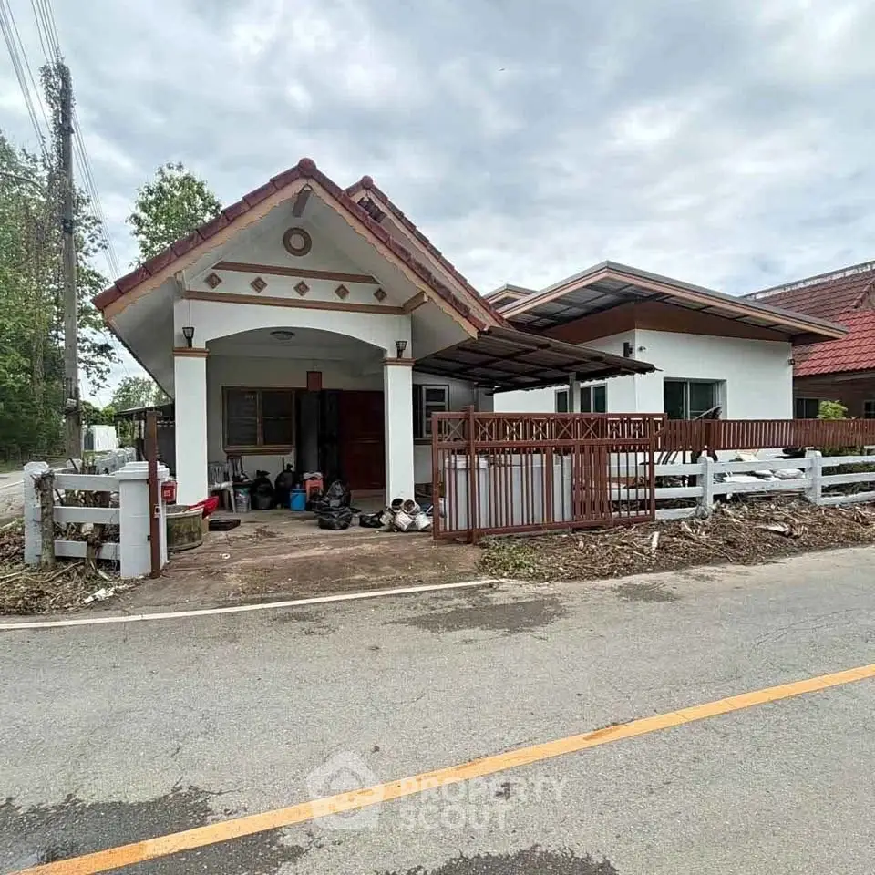 Charming single-story house with traditional roof and fenced yard on a quiet street.