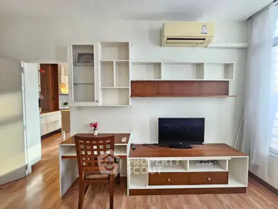 Modern living room with built-in shelves, TV, and air conditioning in a cozy apartment.