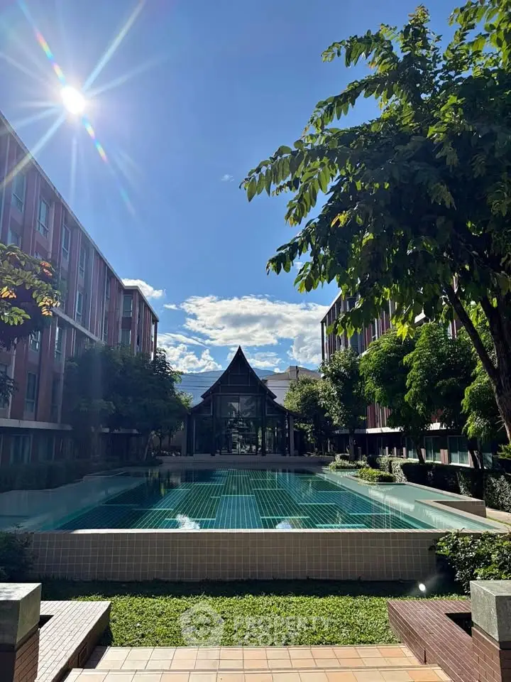 Stunning residential pool area with lush greenery and modern architecture under a bright blue sky.