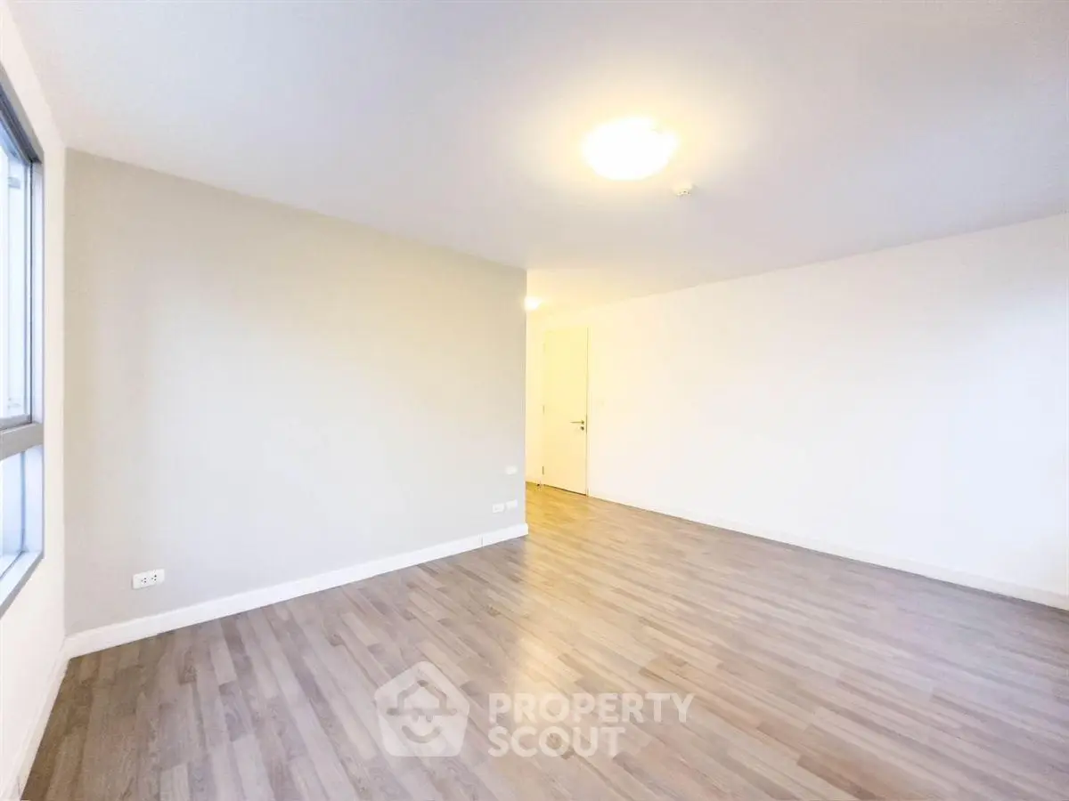 Spacious empty room with wooden flooring and bright lighting, perfect for customization.