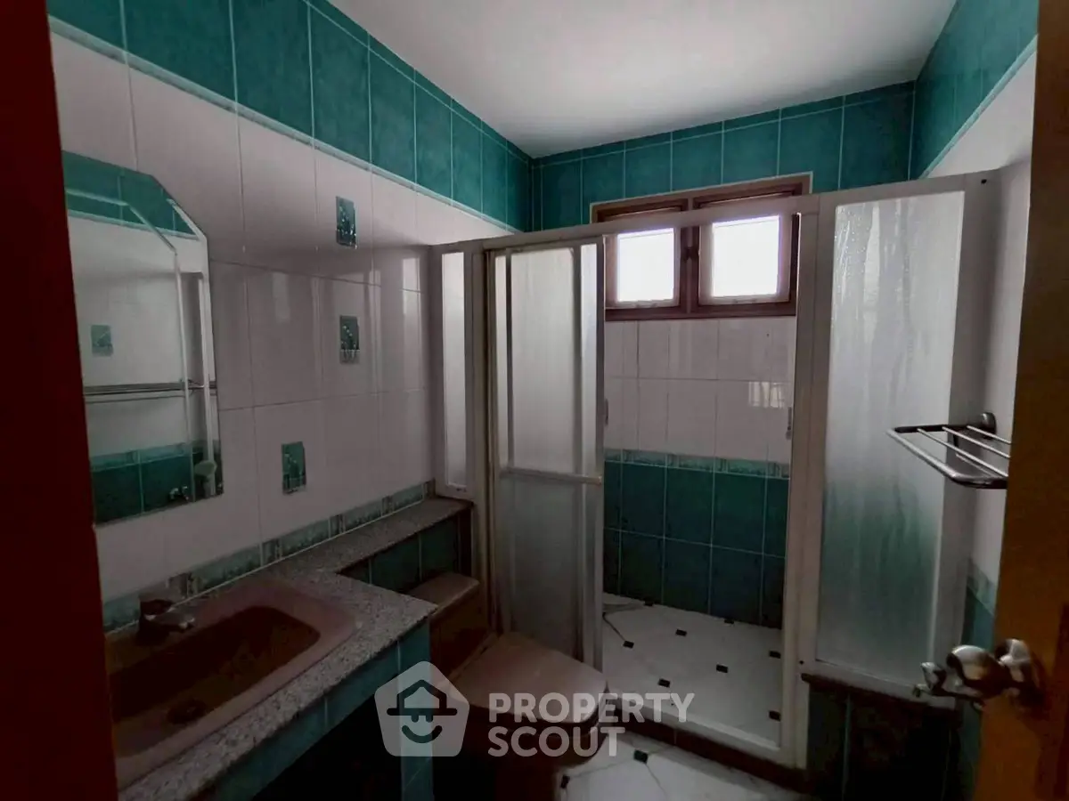 Charming bathroom with teal tiles and modern shower enclosure