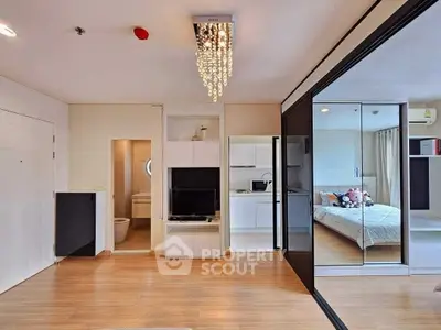 Modern apartment interior with open layout, featuring bedroom, living area, and stylish chandelier.