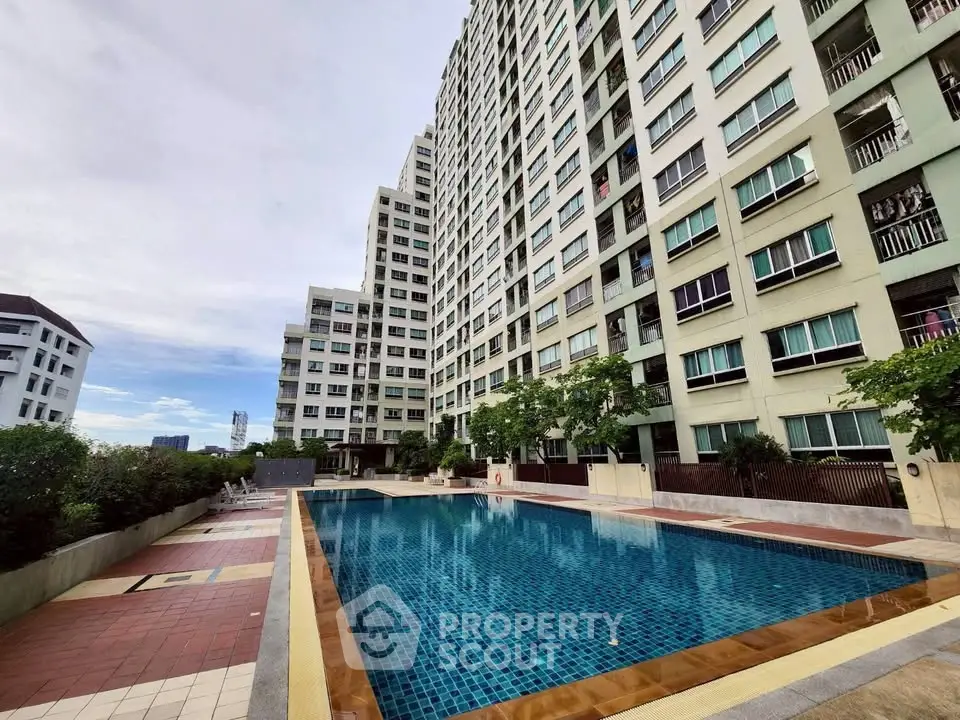 Modern high-rise building with a spacious outdoor swimming pool and lush greenery.