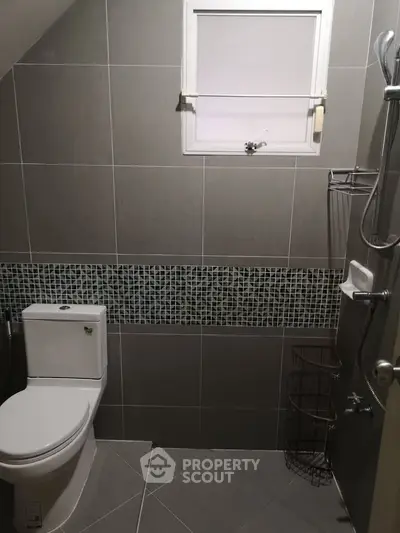 Modern bathroom with sleek gray tiles and stylish mosaic accent wall.