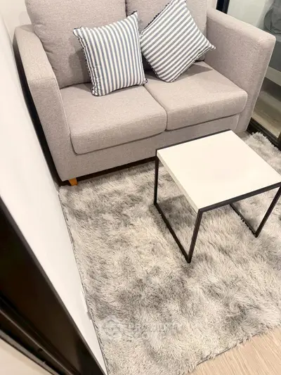 Cozy living room with modern sofa, striped cushions, and plush rug