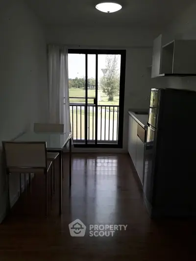 Modern kitchen with open layout and balcony view, featuring sleek appliances and minimalist design.