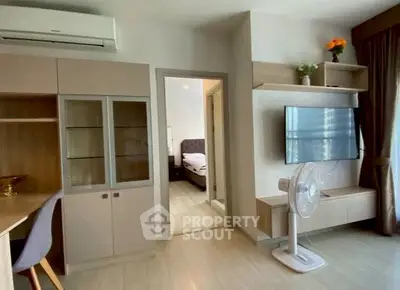 Modern living room with sleek furniture and wall-mounted TV, leading to a cozy bedroom.