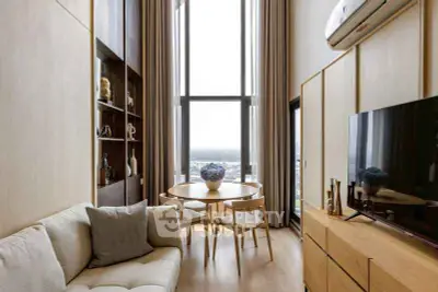 Modern living room with high ceilings and large windows offering stunning city views.