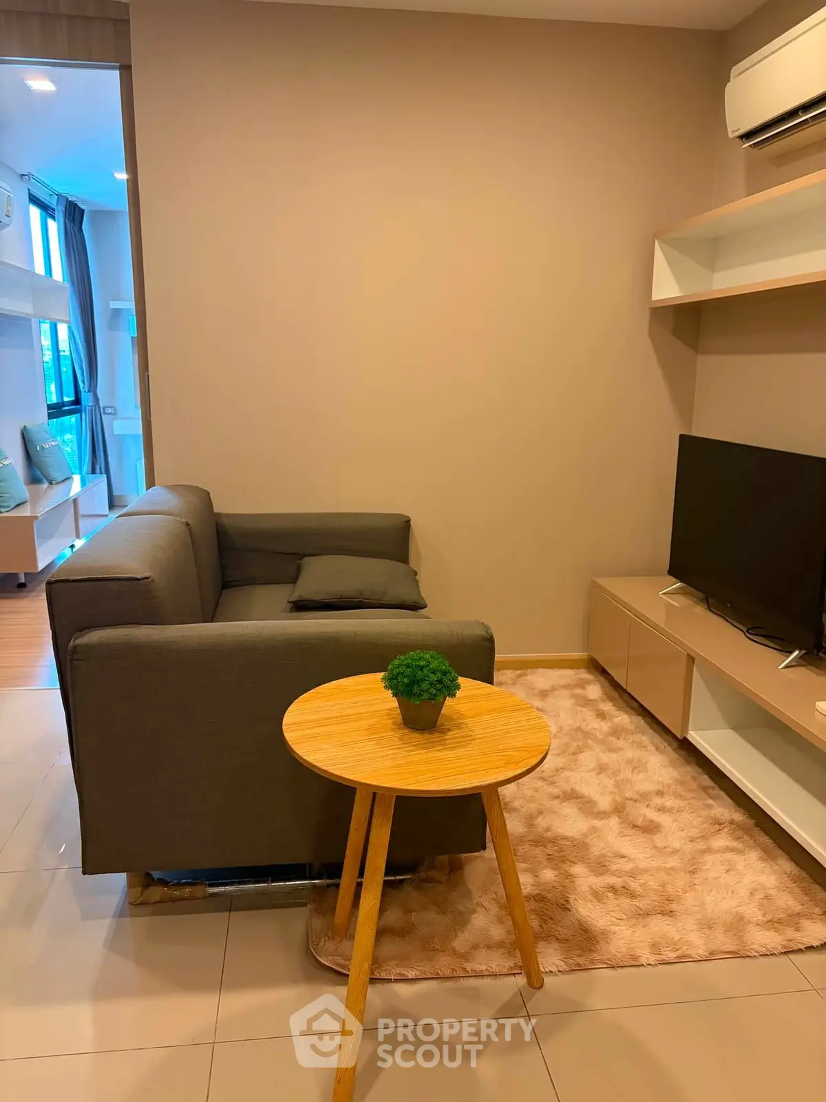 Cozy living room with modern sofa, TV, and air conditioning in a stylish apartment.