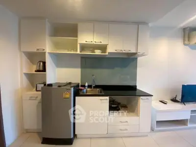 Modern compact kitchen with sleek cabinetry and stainless steel appliances in a cozy apartment.