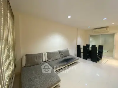 Spacious living room with modern furniture and dining area, featuring sleek design and ample natural light.