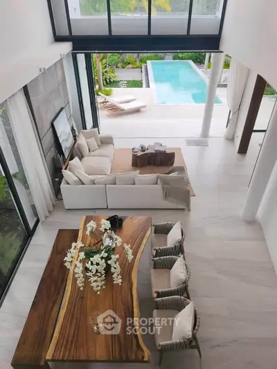 Luxurious open-plan living room with pool view, elegant furniture, and natural wood accents.