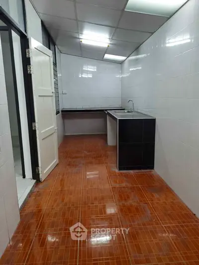 Spacious kitchen with tiled floor and modern sink in a real estate property.