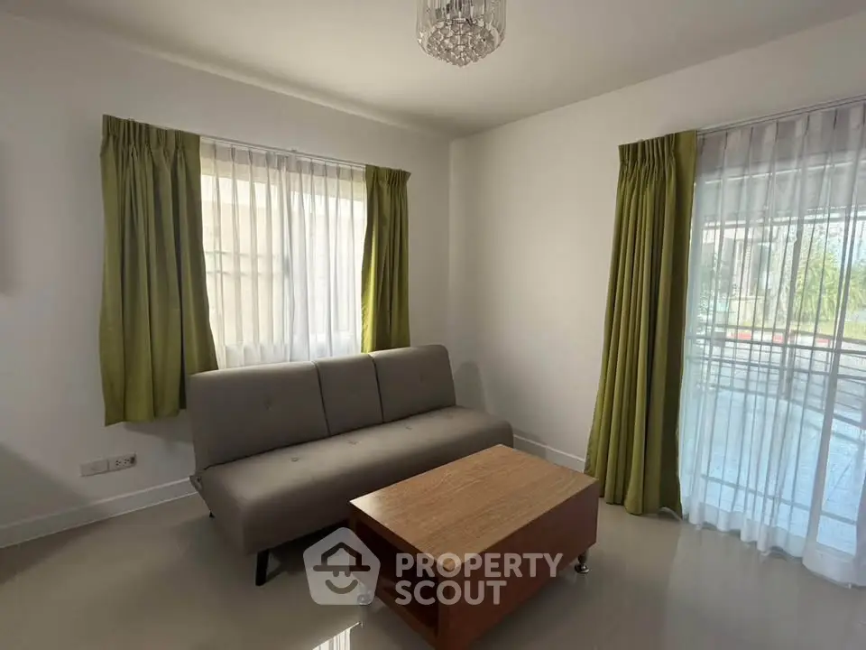 Bright living room with modern sofa and wooden coffee table, featuring large windows with green curtains.