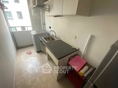Compact kitchen with washing machine and balcony view in modern apartment.