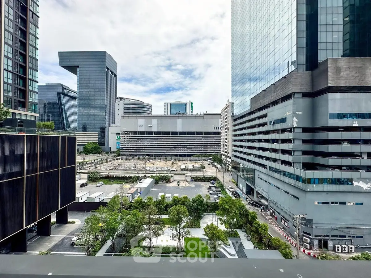 Stunning urban view from a high-rise balcony overlooking modern cityscape and lush greenery.