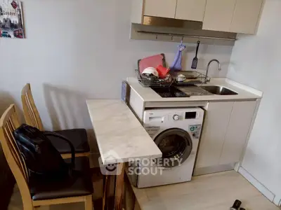 Compact kitchen with washing machine and dining area in modern apartment.