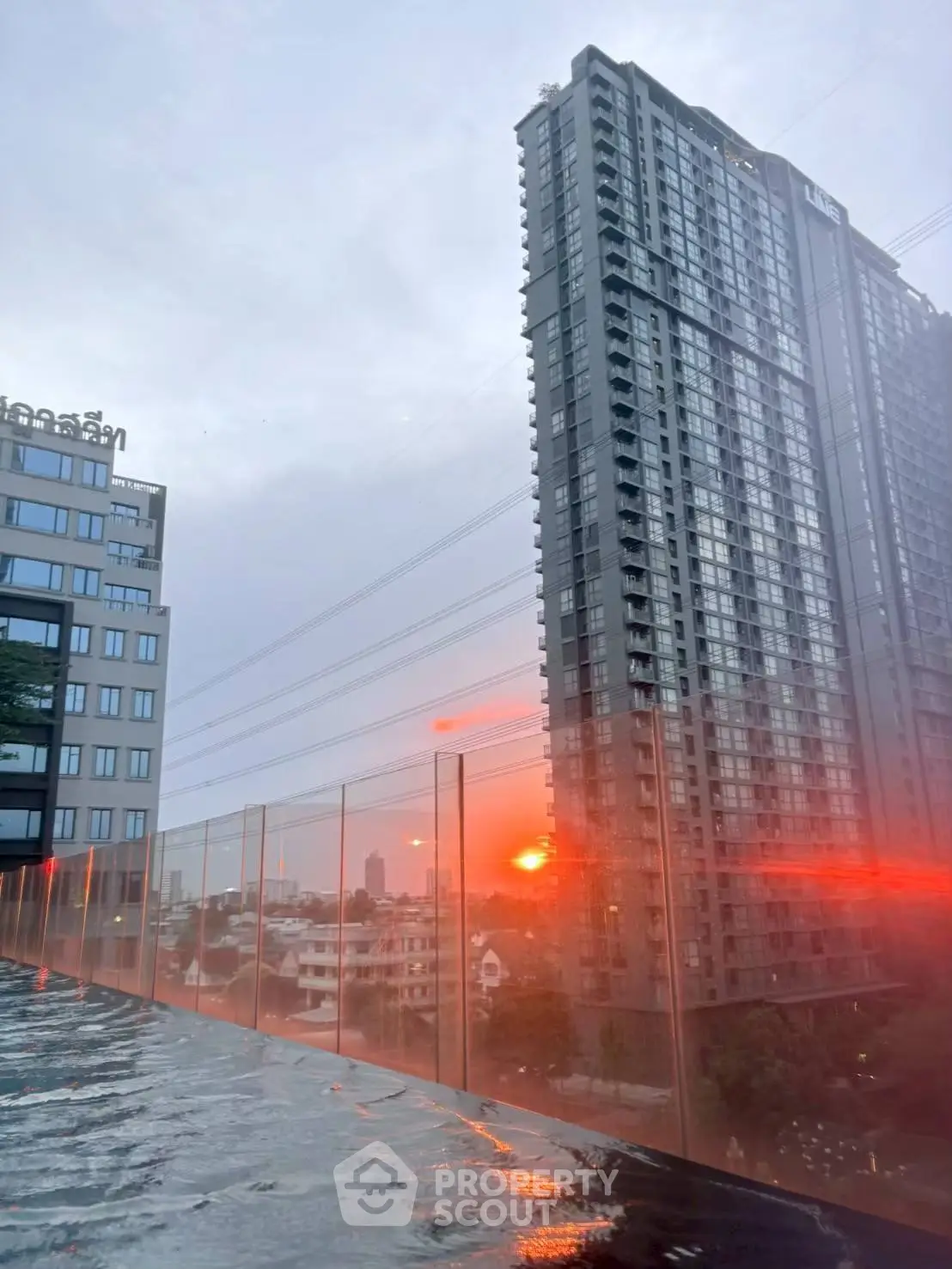 Stunning sunset view from a modern high-rise building with glass balcony and cityscape.