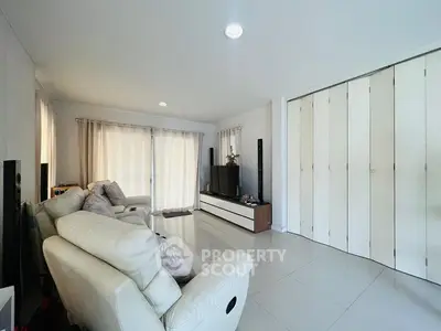 Spacious modern living room with white leather sofas and sleek entertainment center.