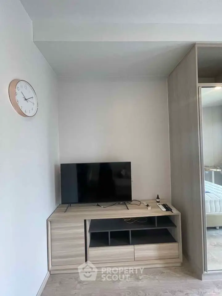 Modern living room with sleek TV stand and wall-mounted clock, minimalist design.
