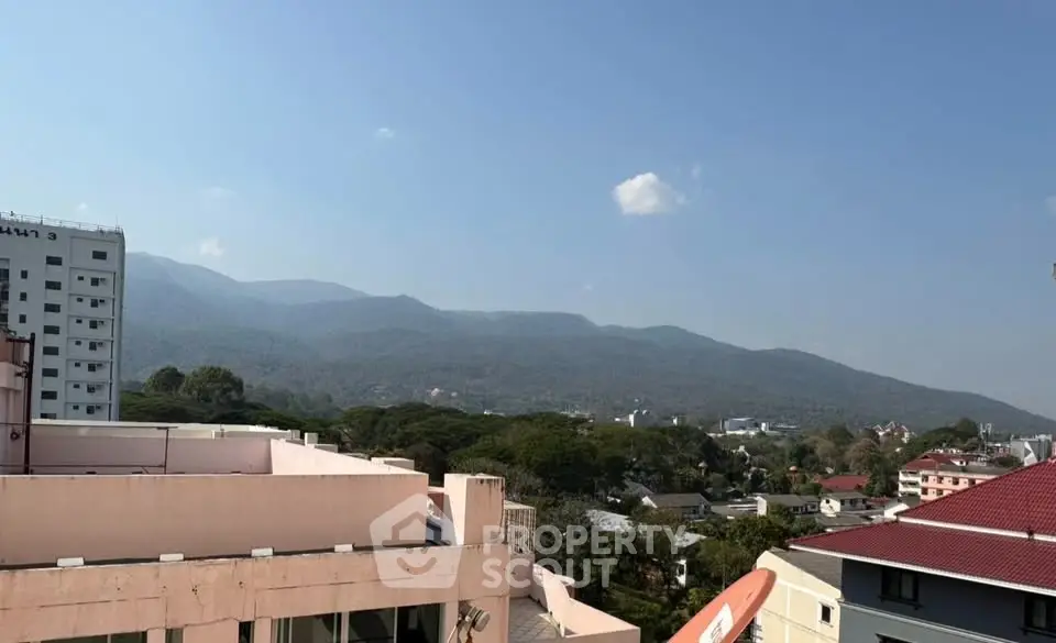 Scenic mountain view from urban rooftop with clear blue sky.