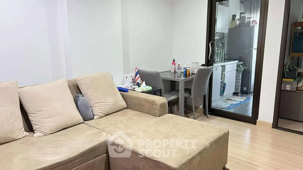 Cozy living room with beige sofa and dining area in modern apartment