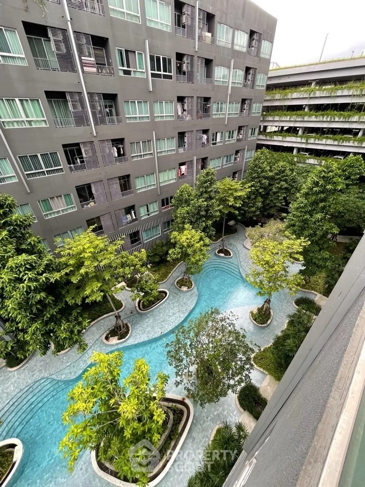 Modern apartment building with lush garden and winding pool view