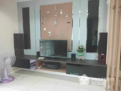 Spacious living room with large wall clock, mirrored wall, and modern entertainment system, ideal for family gatherings and relaxation.