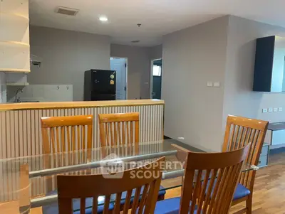 Spacious dining area with wooden chairs and open kitchen layout in modern apartment.