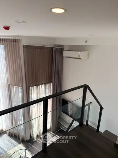 Modern loft interior with glass railing and large windows
