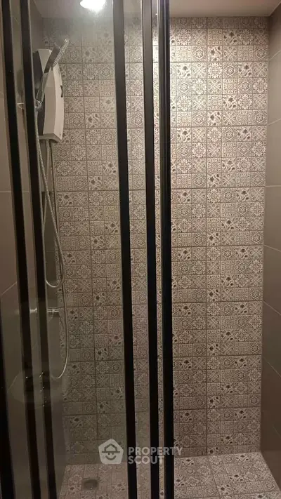 Modern bathroom shower with patterned tiles and glass door enclosure.