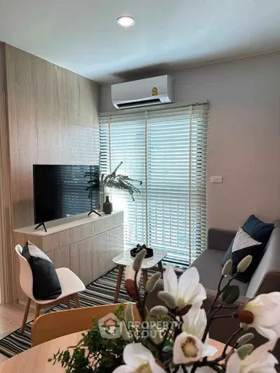 Modern living room with stylish decor, featuring a cozy sofa, flat-screen TV, and natural light from large windows.