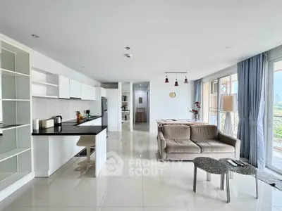Spacious open-plan living room with modern kitchen and balcony view.