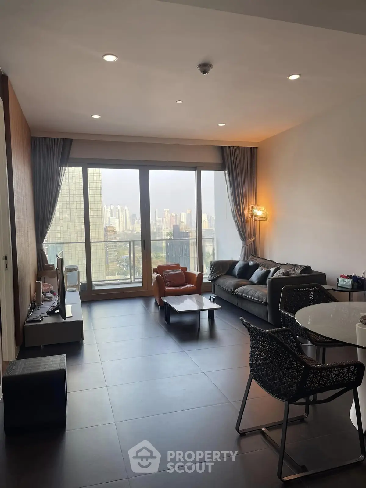 Modern living room with city view, stylish furniture, and large windows in a high-rise apartment.
