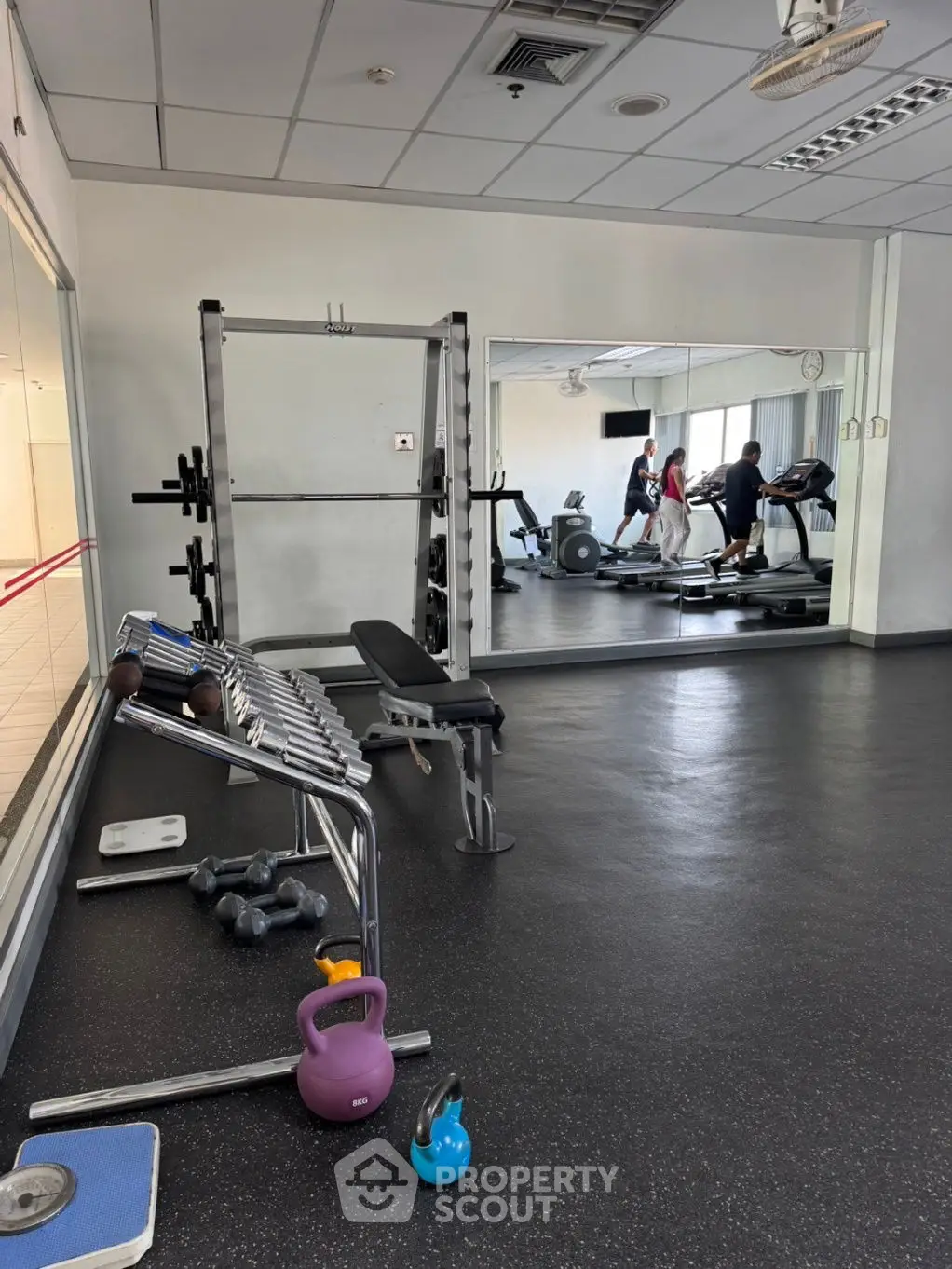 Spacious gym with modern equipment and large mirrors in a residential building.