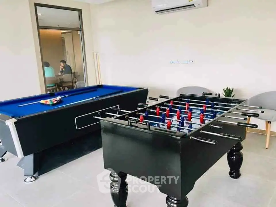 Modern game room with pool and foosball tables in a stylish residential complex.