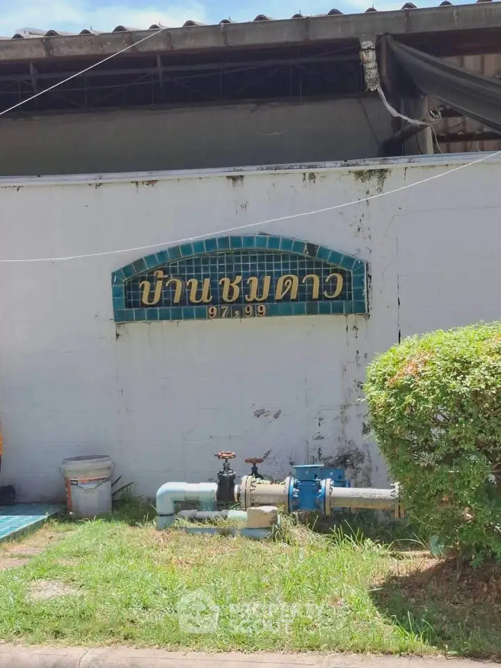 Exterior view of a building with a tiled sign and garden area.