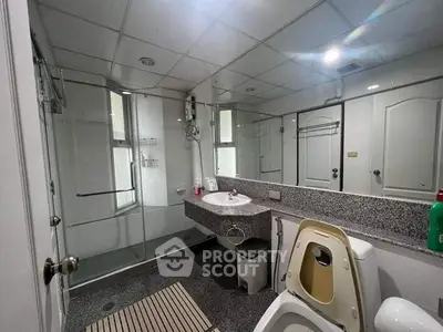 Modern bathroom with glass shower, granite countertop, and ceiling lights.