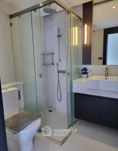 Modern bathroom with glass shower, sleek vanity, and elegant lighting