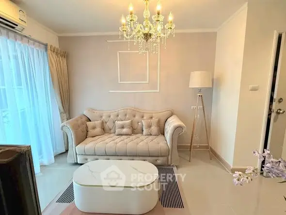 Elegant living room with chandelier and plush sofa in modern apartment.