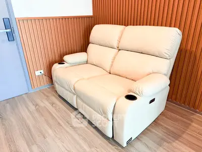 Modern living room with stylish beige recliner sofa and wooden panel wall.