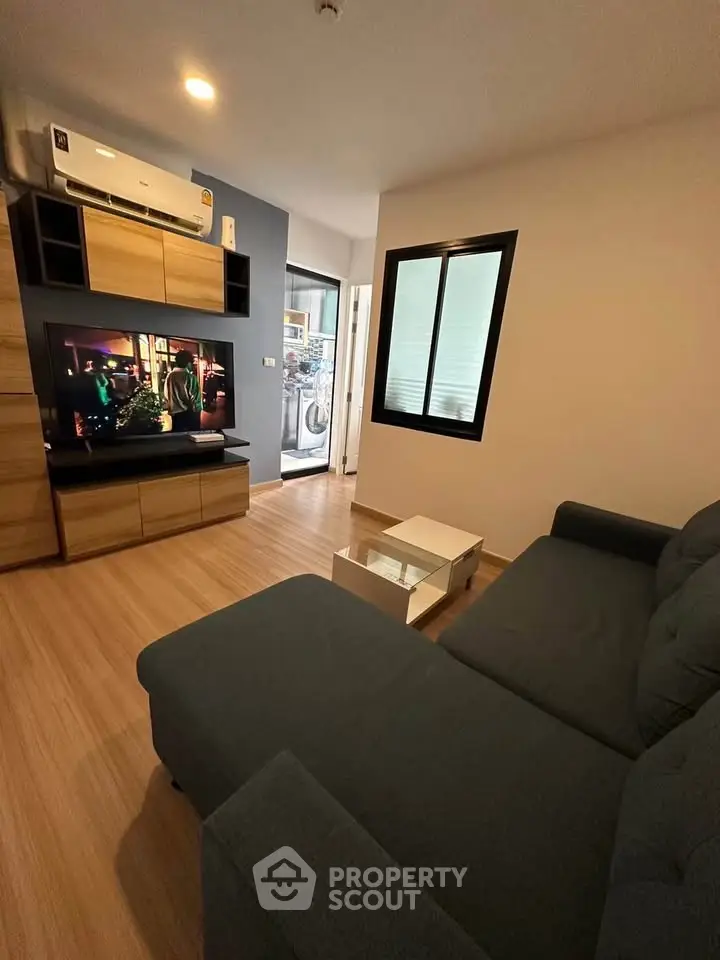 Modern living room with cozy sofa and wall-mounted TV, featuring stylish wooden flooring.