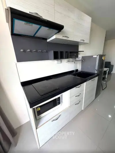 Modern kitchen with sleek cabinetry, induction cooktop, and built-in microwave in a stylish apartment.
