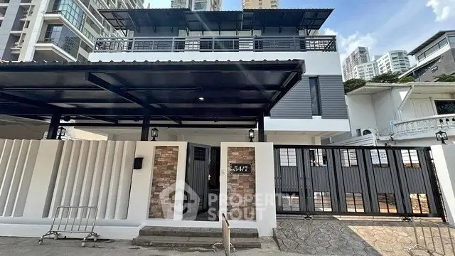 Modern multi-story house with sleek design and gated entrance in urban setting.