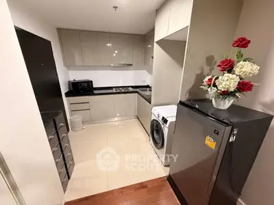 Modern kitchen with sleek cabinets, washing machine, and compact fridge in a stylish apartment.