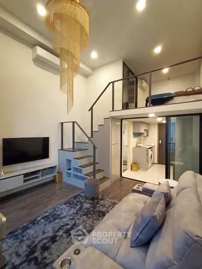 Modern loft apartment with stylish living room and mezzanine bedroom, featuring elegant chandelier and open kitchen.